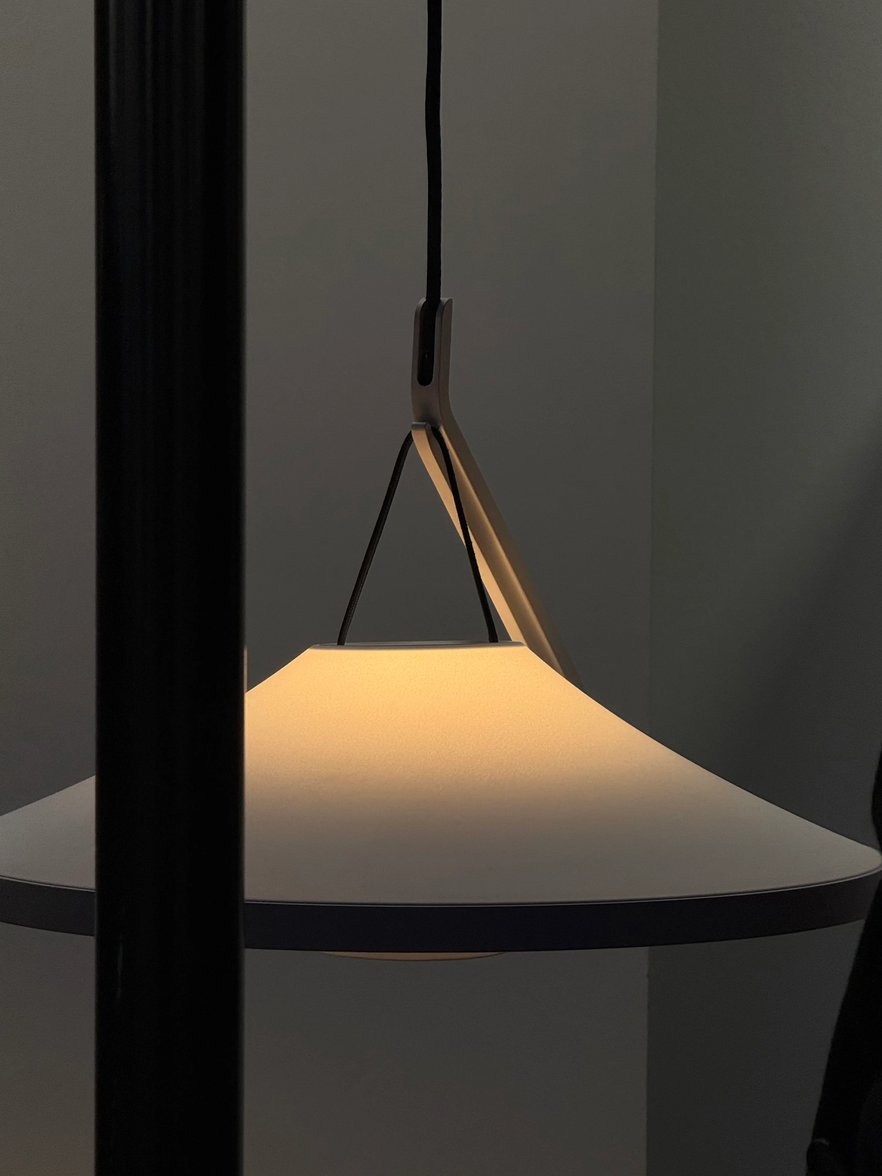A glowing pendant lamp framed by dark vertical structures.