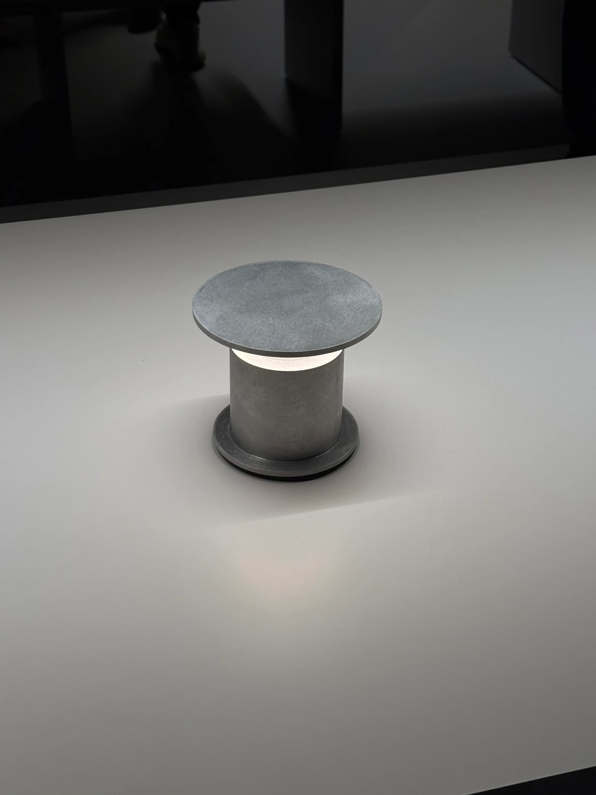A small cylindrical table lamp casting a pool of light.